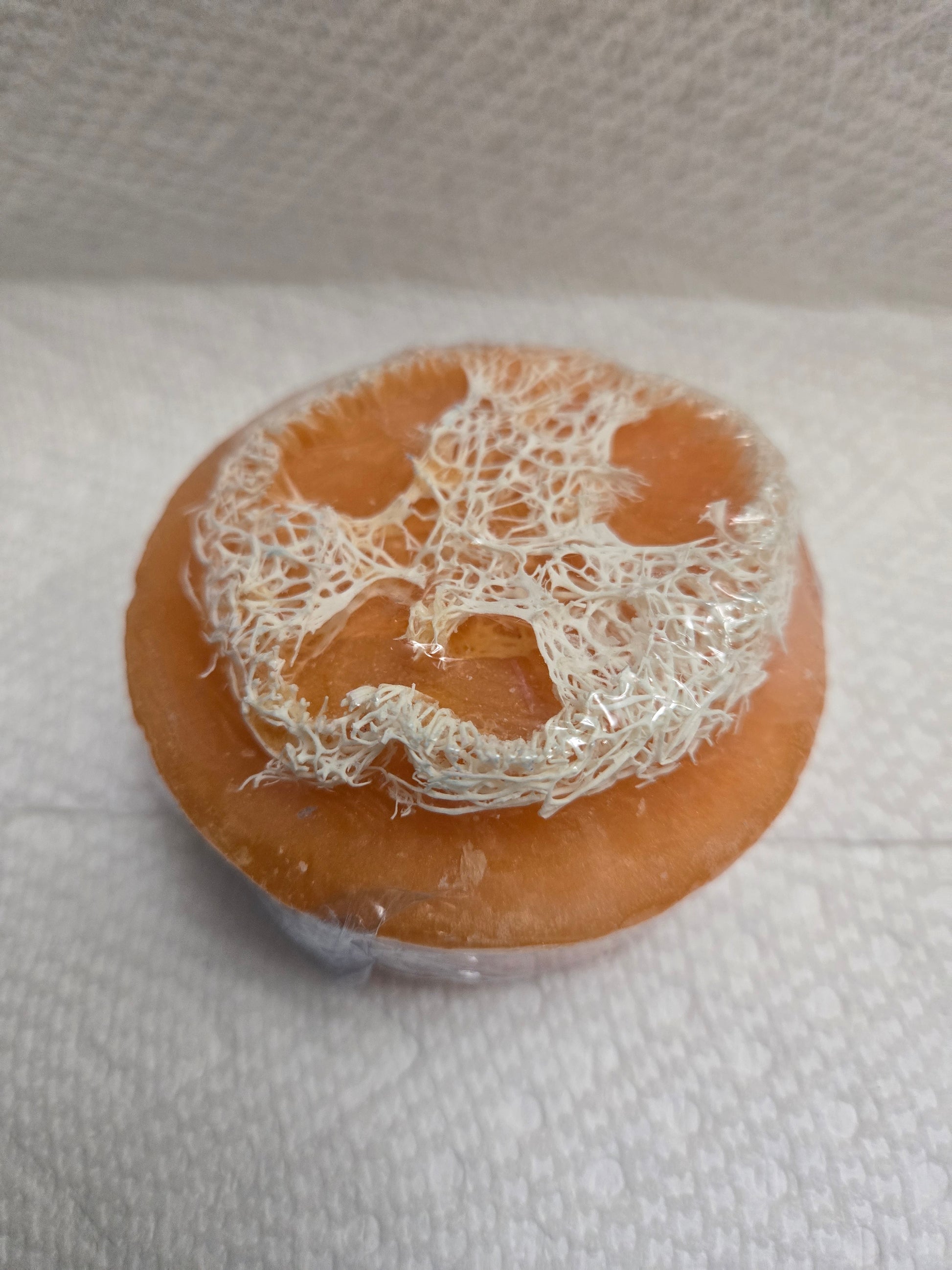 Zaya Soaps Orange Loofah Soap Top view of a round orange handmade soap with natural loofah texture embedded in the center By Zaya Soaps LLC